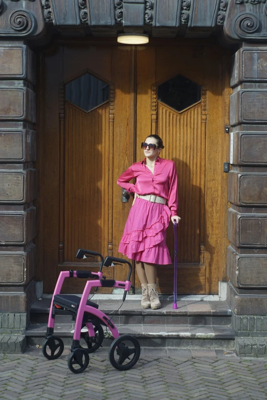 the woman in the pink dress is posing for a po with a baby carriage