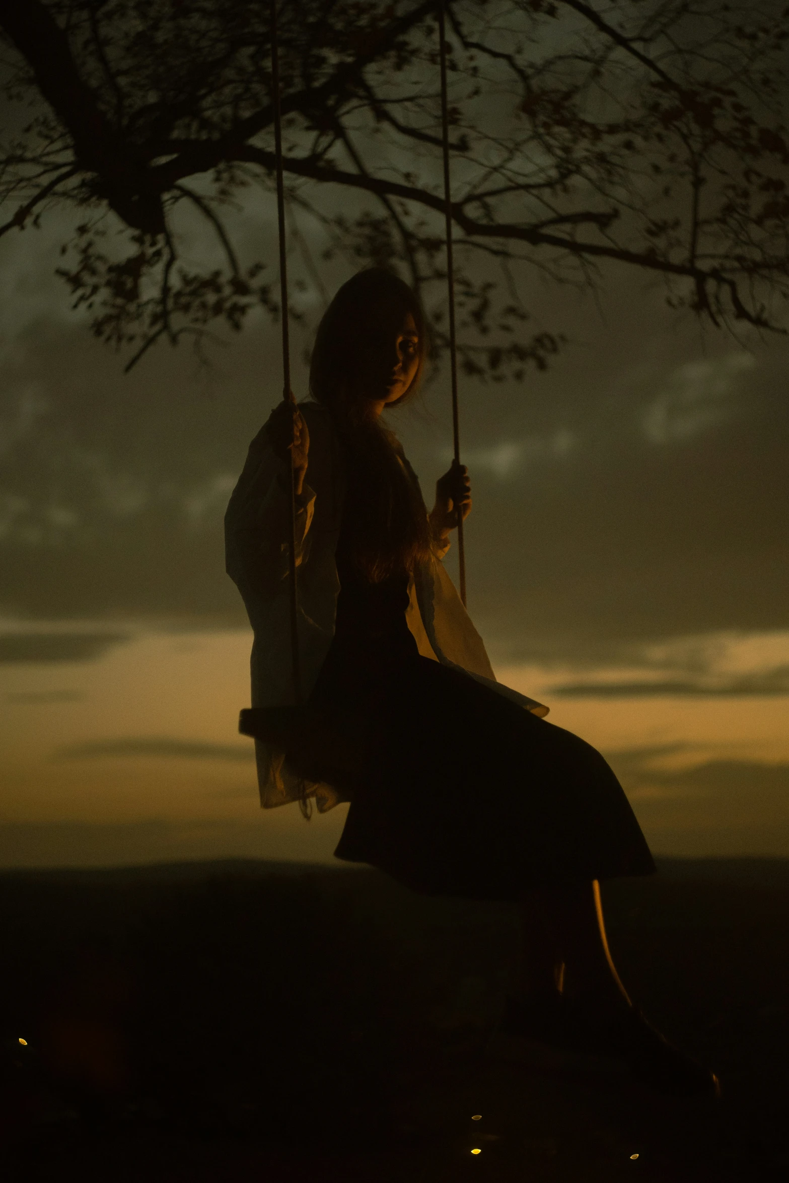 a woman in dress on a swing at night