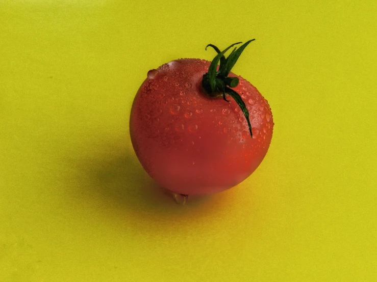 a large red tomato sitting on top of a yellow counter