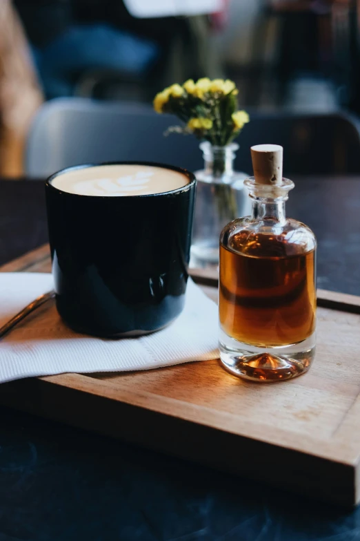 a cup of coffee and an old bottle on a tray