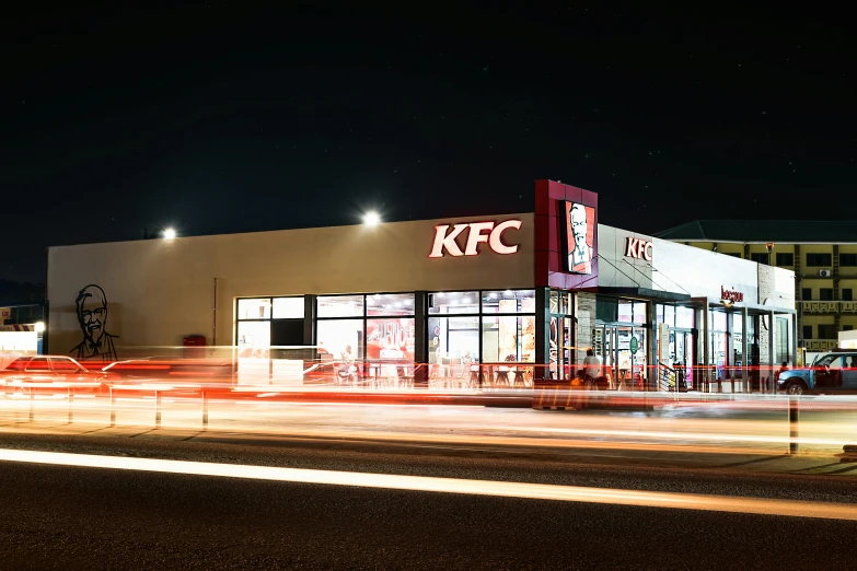 a lit up kfc is next to a building