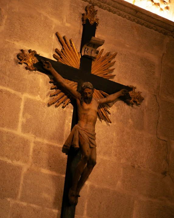 cross with golden cross and large statue on brick wall