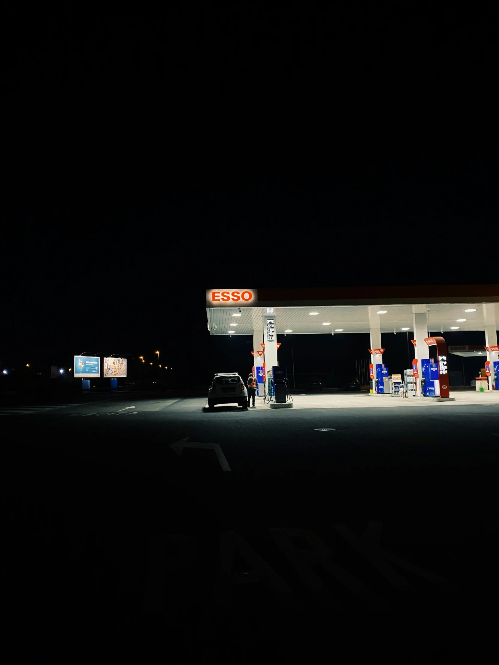 gas station at night time with car parked on street