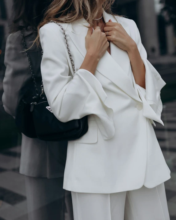 a woman standing in front of a building adjusting her collar