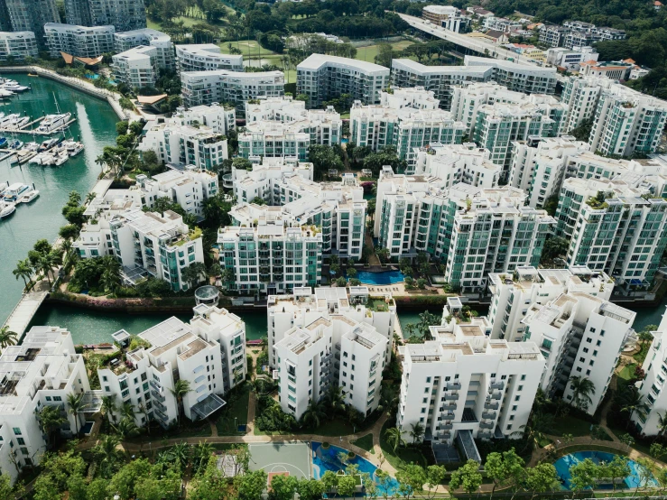 an aerial view of several white buildings and trees next to the ocean