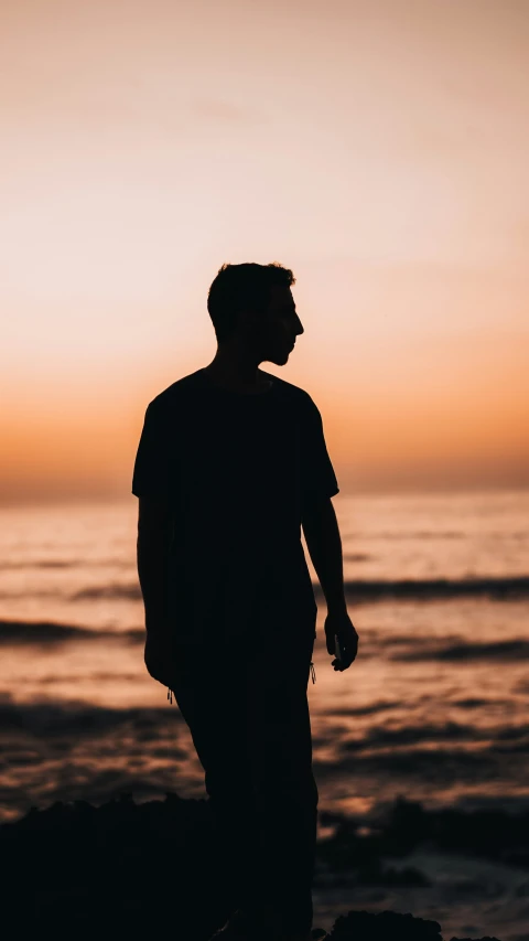 a man standing on the shore at sunset