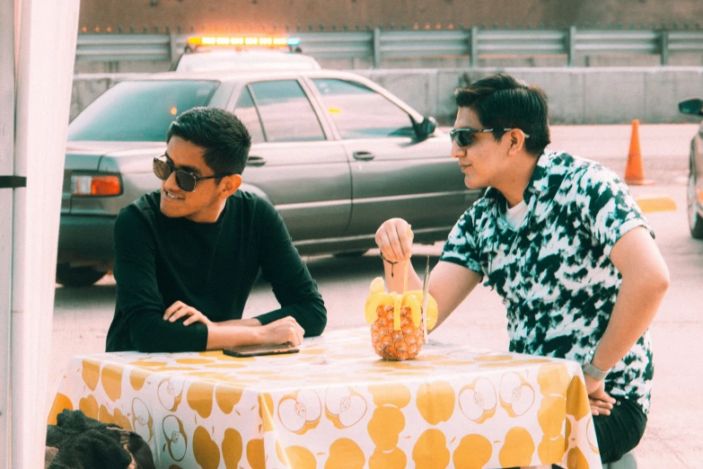 two people standing at a table that has food on it