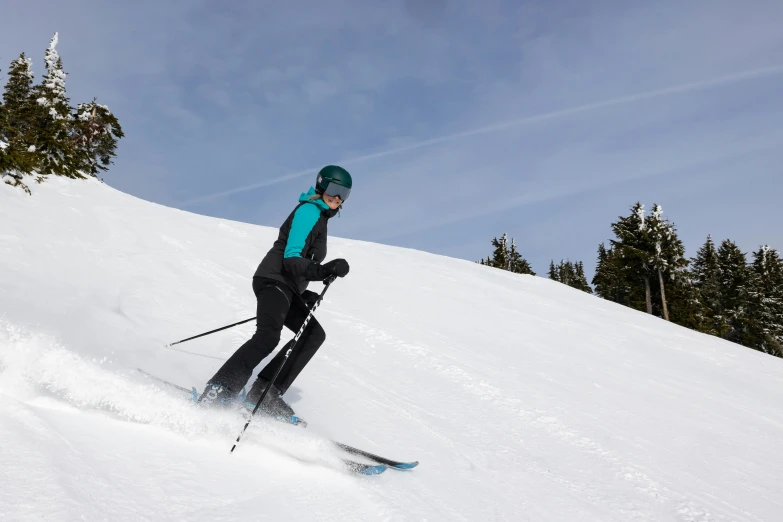 the skiier in the green jacket is going down the hill