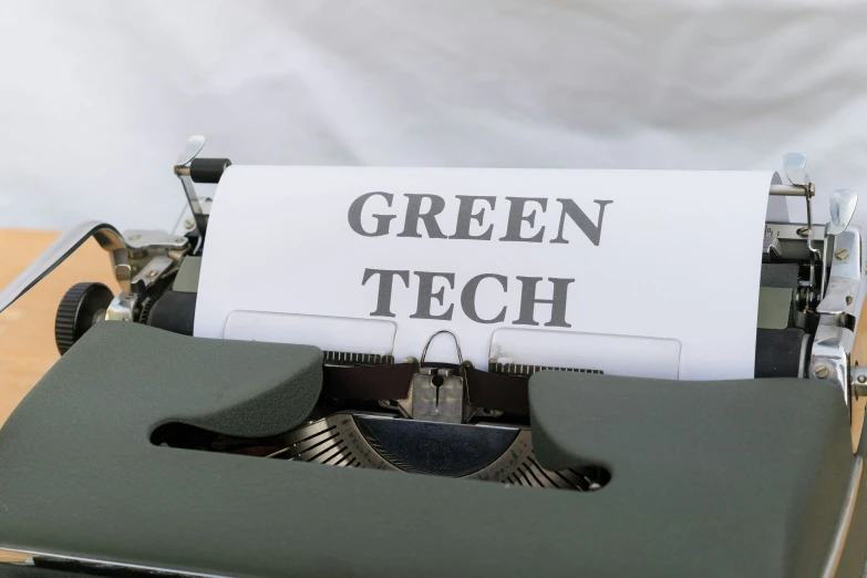 a close up of a typewriter with a white paper that reads green tech