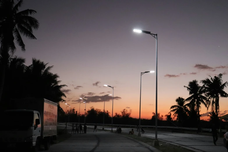 the sun is setting over a palm tree lined street