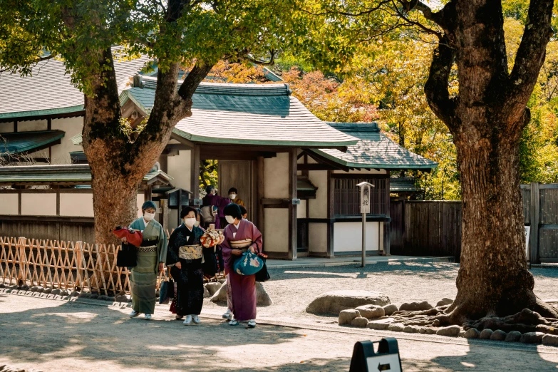 oriental people in front of a shrine, a bench, and a tree