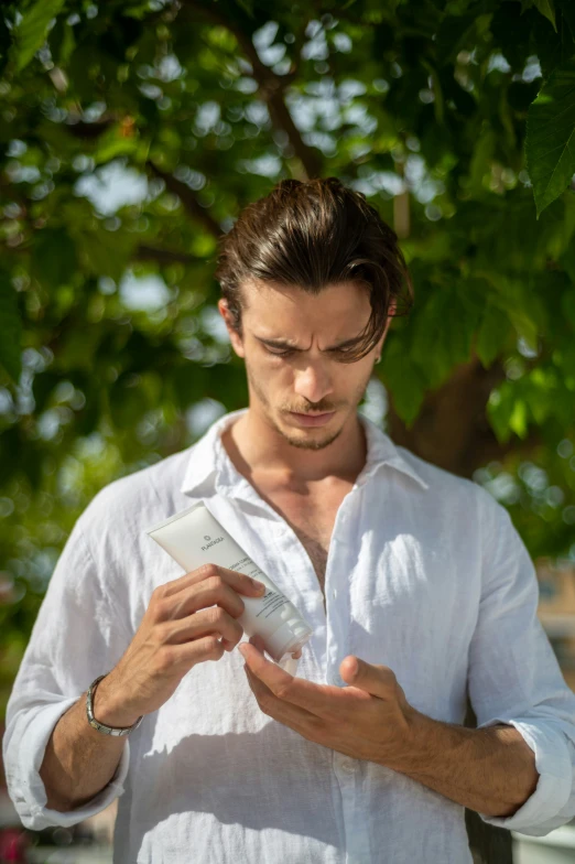 man standing outdoors and looking down at cell phone