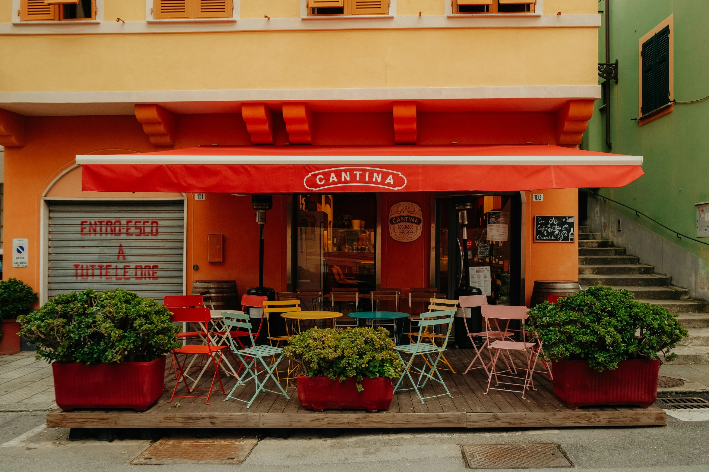 a red awning over an outdoor restaurant with green plants