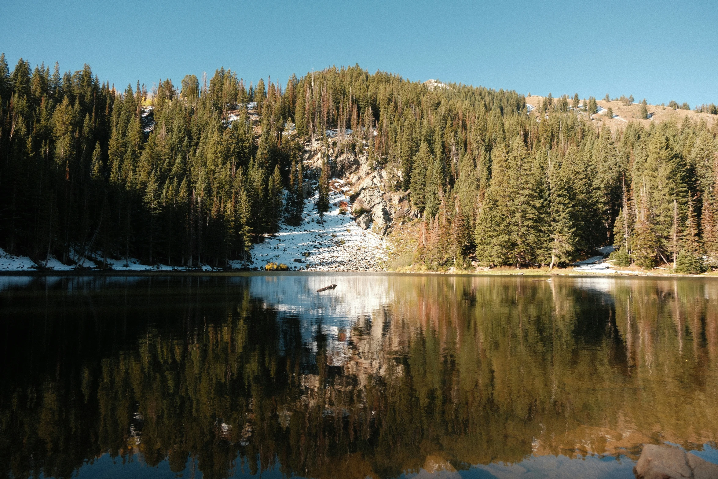 the trees around the hill are reflected in a lake