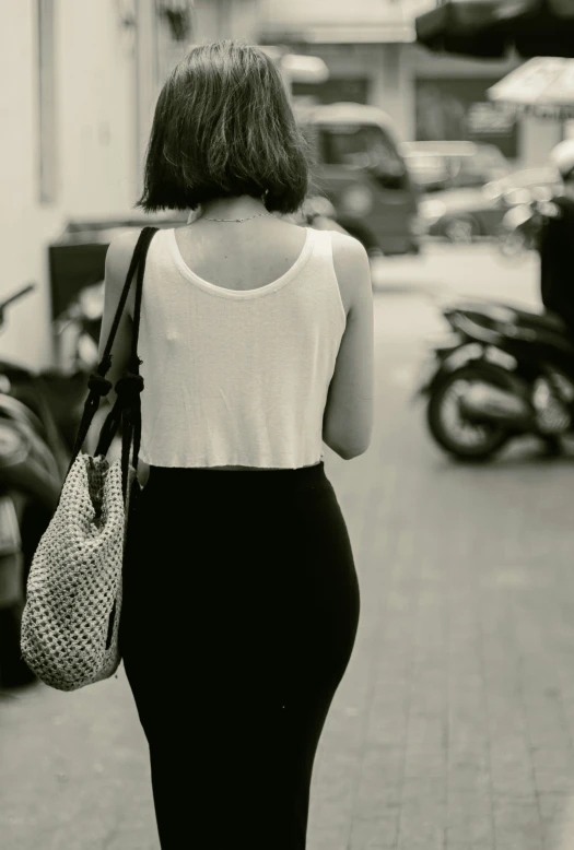 a woman walking down the road holding a purse