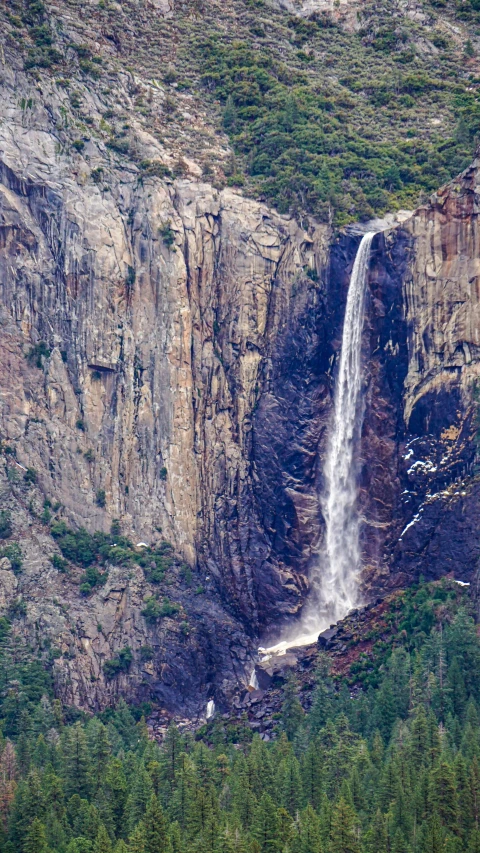 large waterfall pouring down into the hillside in the mountains