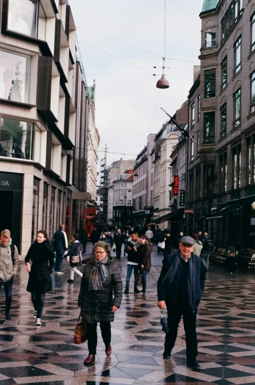 pedestrians walking around in a busy sidewalk on a rainy day