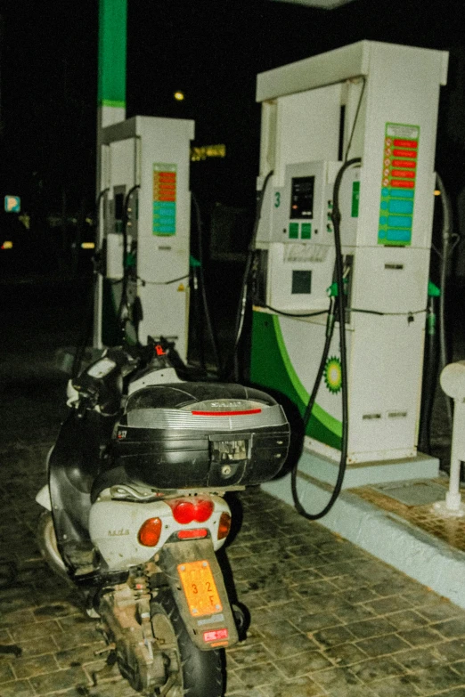 motorcycle parked at the gas pump in front of a fuel pump