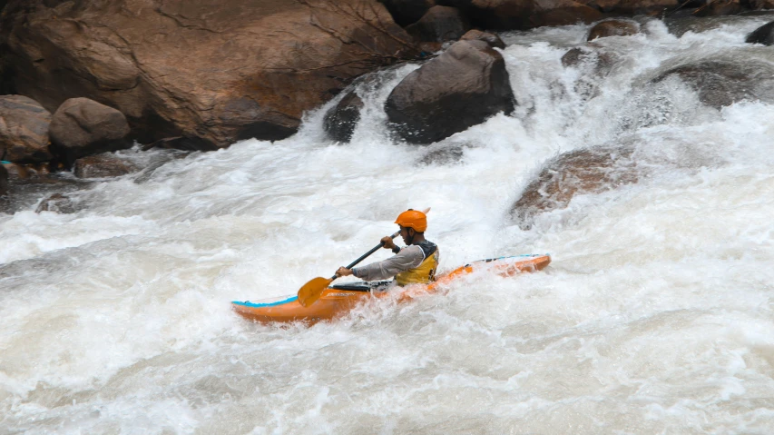 a man in a kayak rides down a rushing river