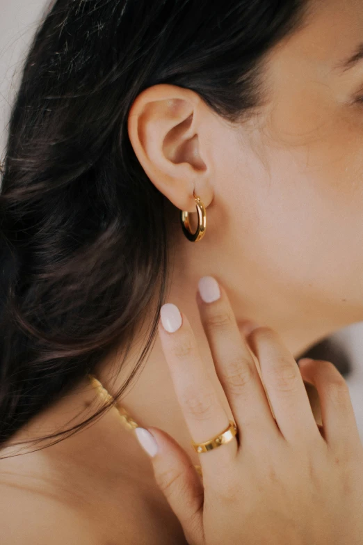 a woman wearing gold earrings and necklace