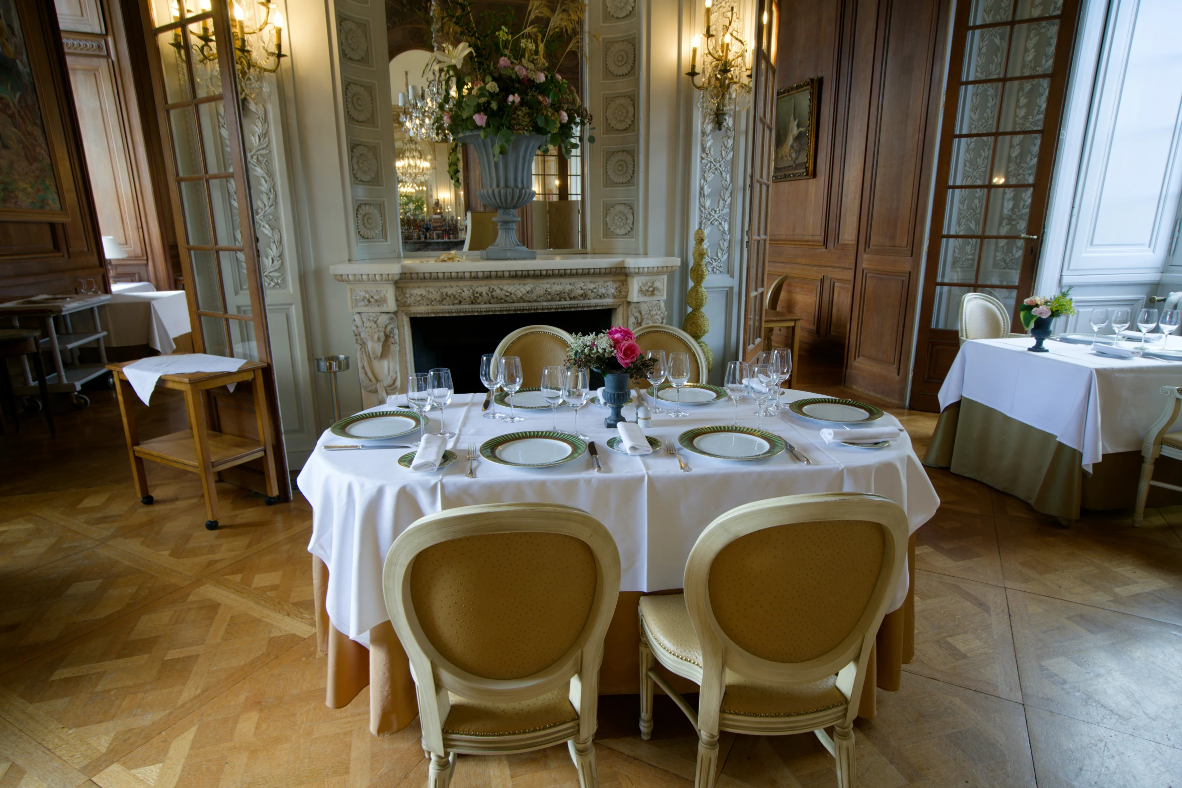 there are two tables set up with chairs in front of the fireplace