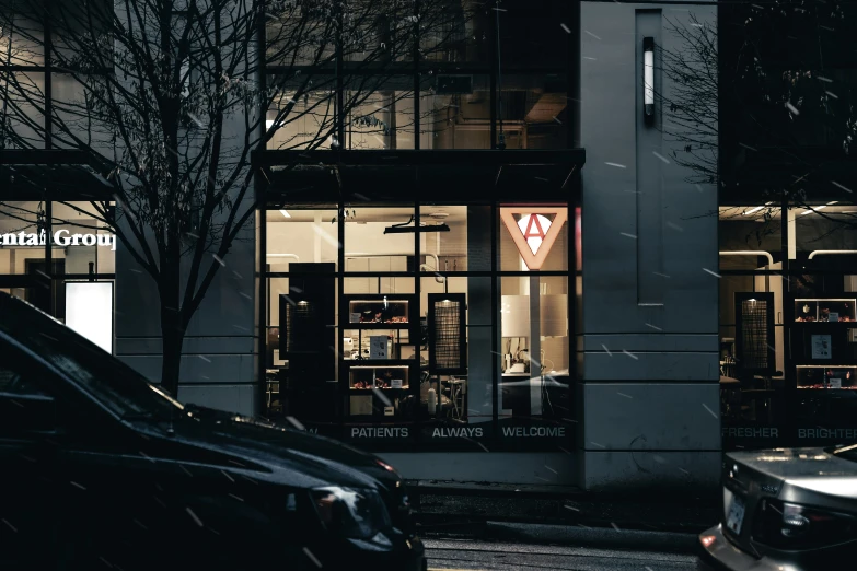 a store lit up at night with cars parked