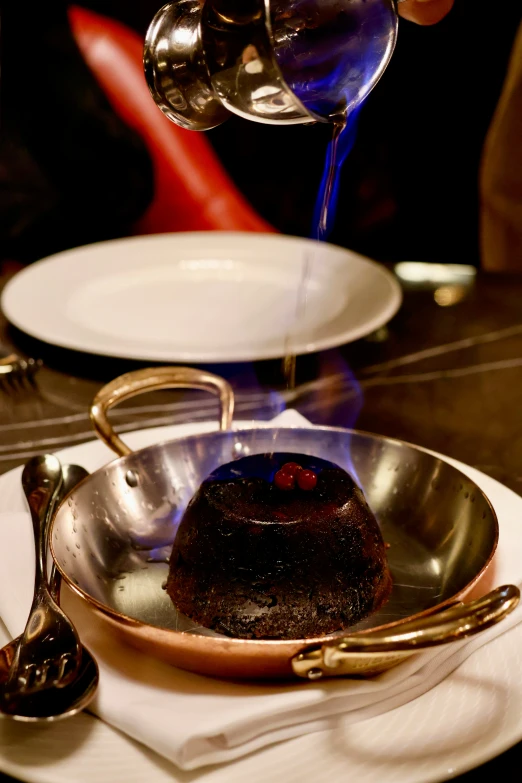 a person pouring wine over a chocolate desert