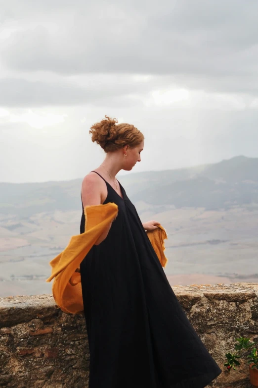 there is a woman with a yellow and black dress looking out over a hill