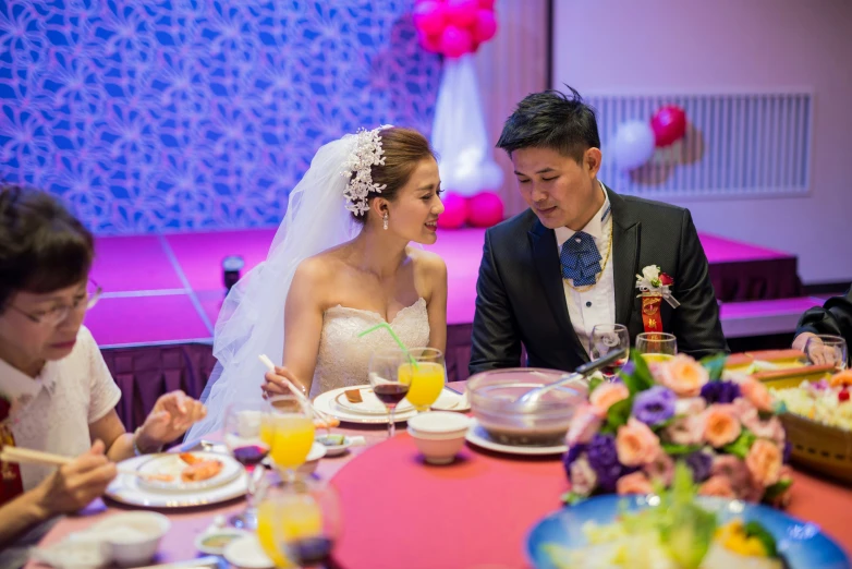 a bride and groom with guests eating their meal