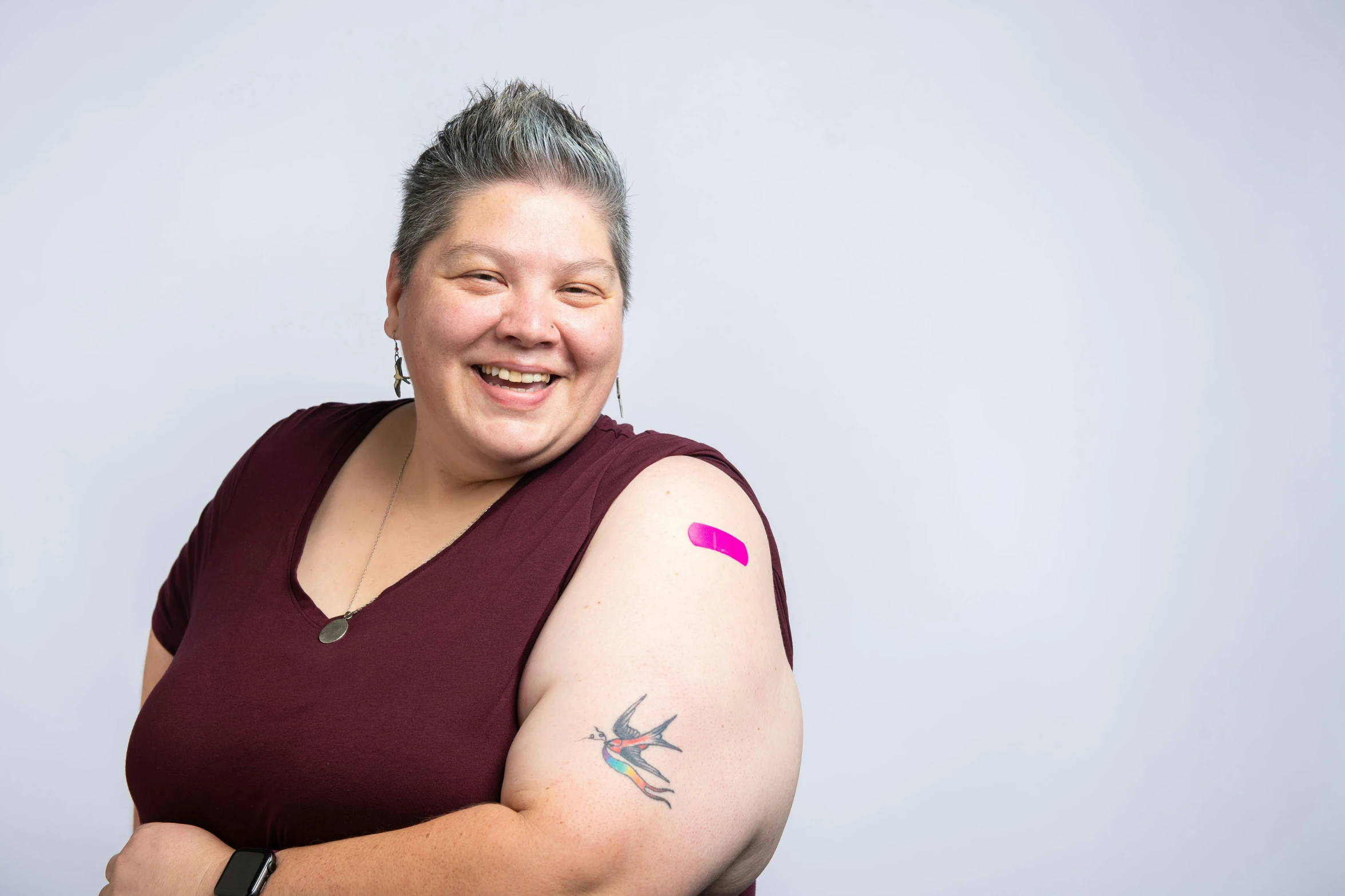 a woman wearing a purple shirt has tattoos on her arm