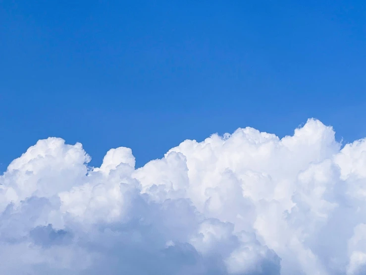 a jet flying through a cloud filled blue sky