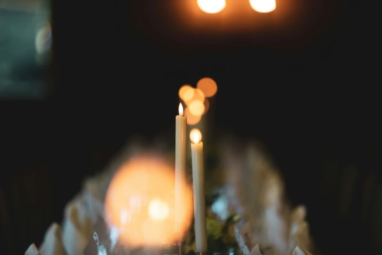 candles are on the candlesticks while a woman watches from behind