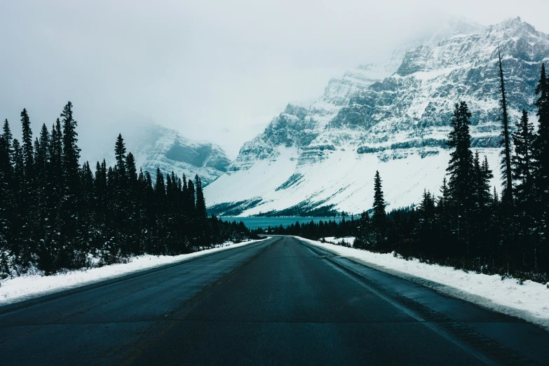 there is a snow covered mountain behind the road