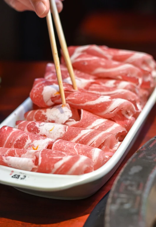 a person is holding chopsticks over some raw food