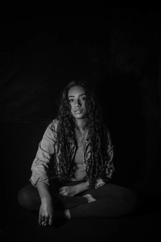 a woman sitting down in the dark looking up at the camera