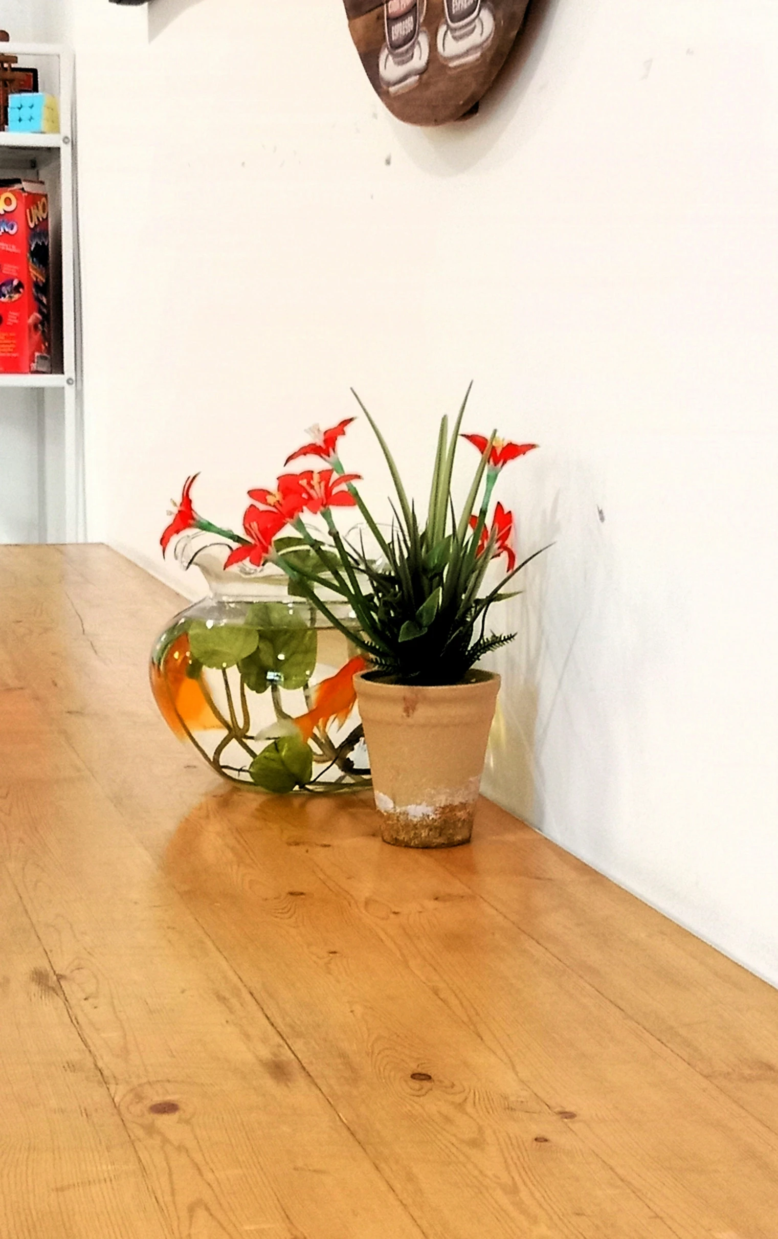 a brown table topped with a potted plant and vase filled with orange flowers