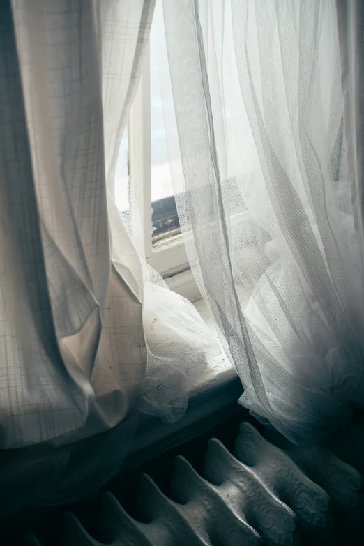 the window with sheer white curtains is open