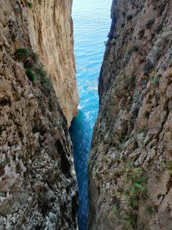 a boat is cruising along the narrow canal on the side of a cliff