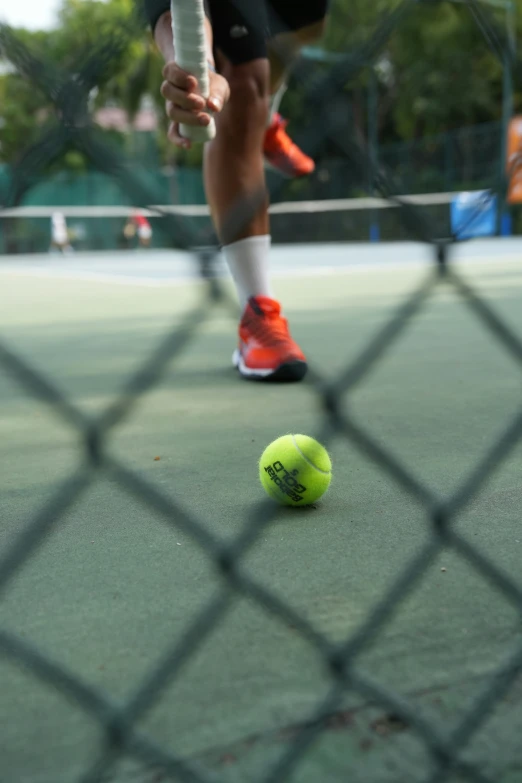 a man bending down to pick up a tennis ball