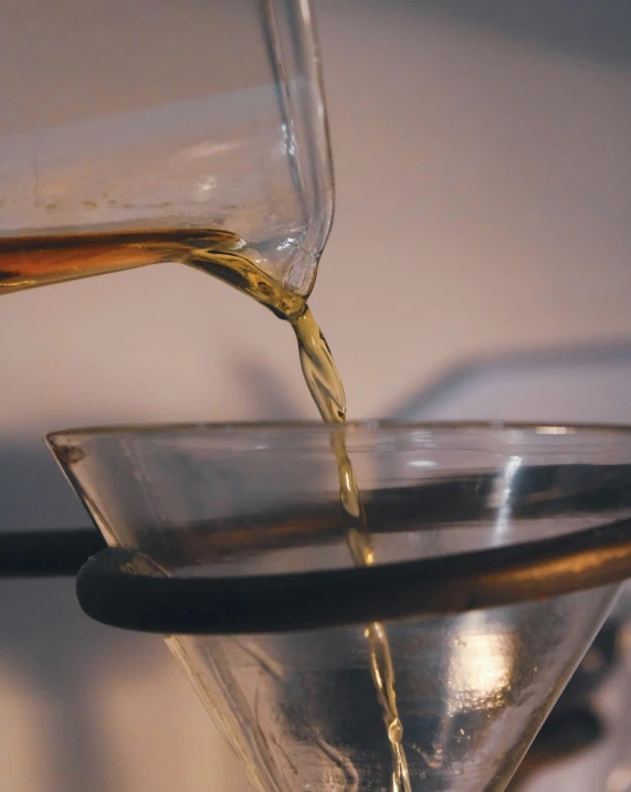 a glass pitcher pouring an alcoholic drink into a bowl