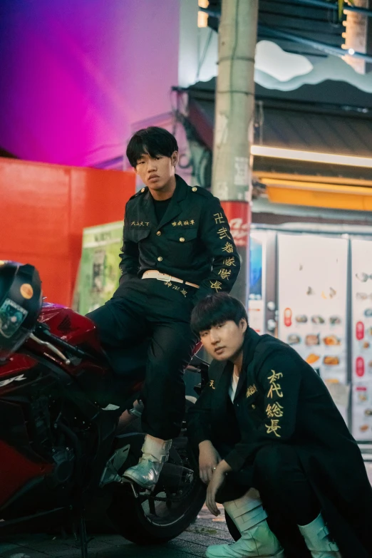 two young men are sitting on the top of a motorcycle