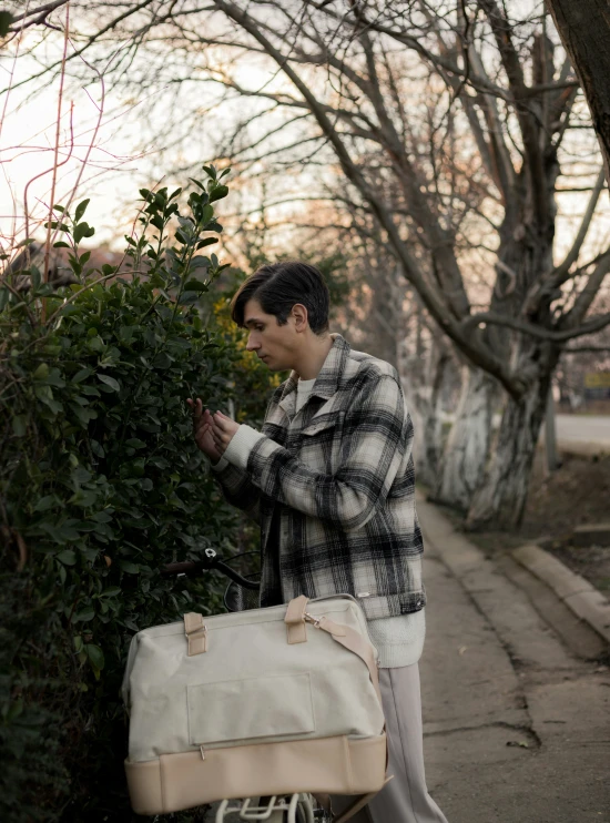 a man standing next to a bush with a suitcase