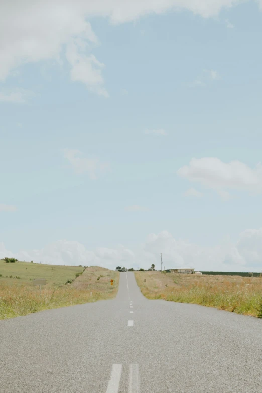 a street lined with grass and dirt next to an empty road