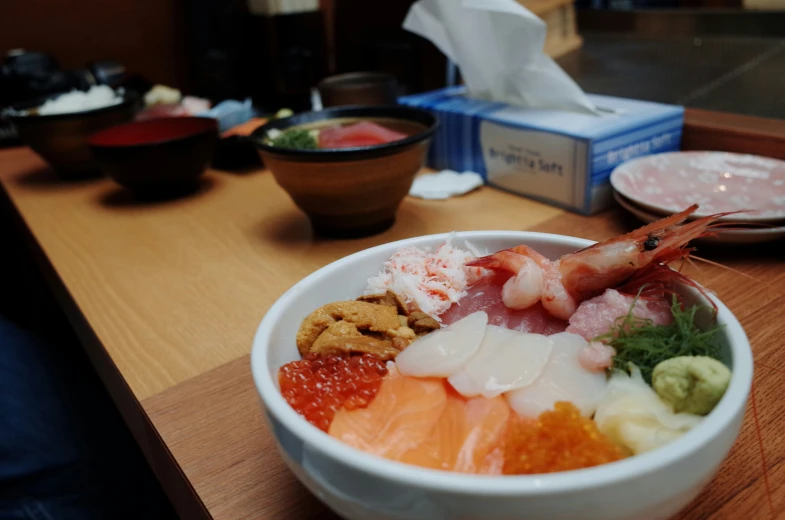 a bowl filled with assorted food on top of a wooden table