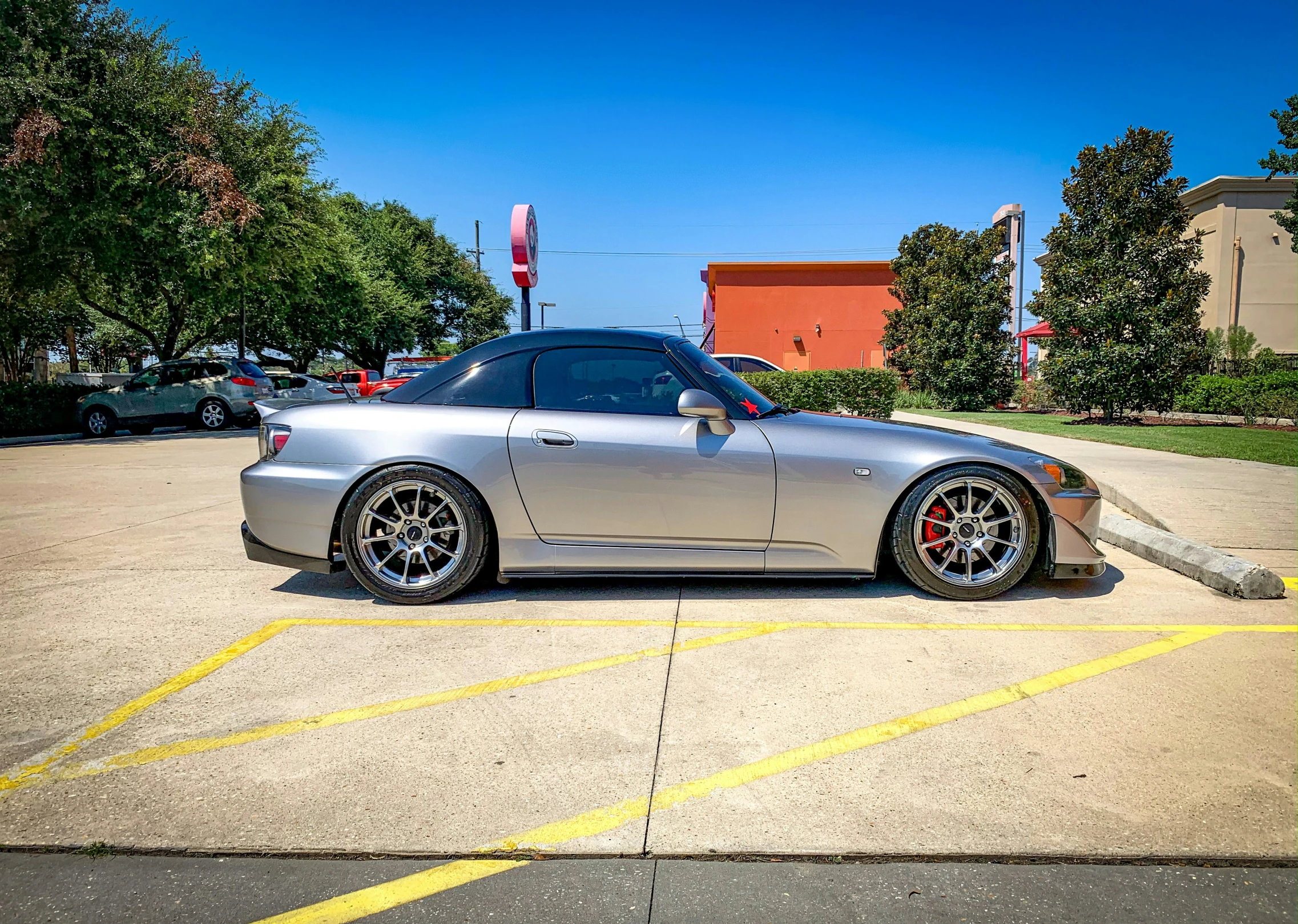 a car in a parking lot with trees in the background