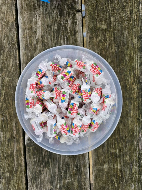 a bowl full of different colored candies and paper clips