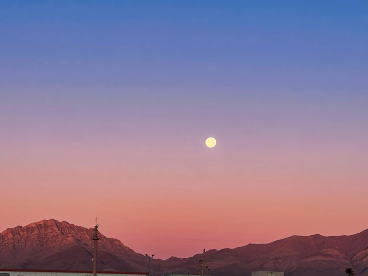 the setting sun is seen over mountains on a clear day