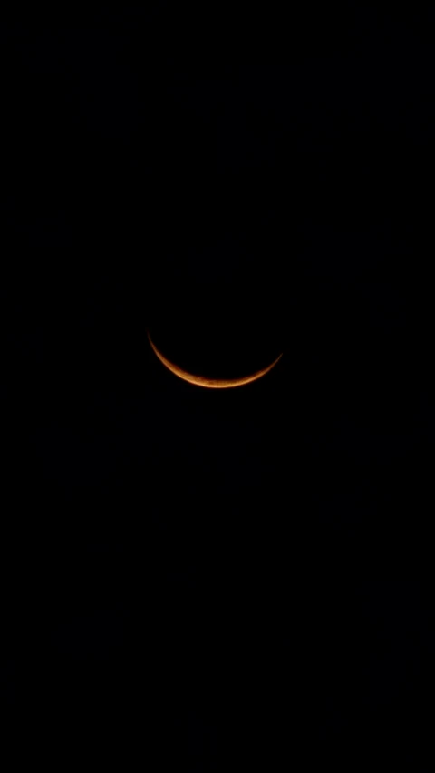 the moon partially obscured by the crescent in the dark sky