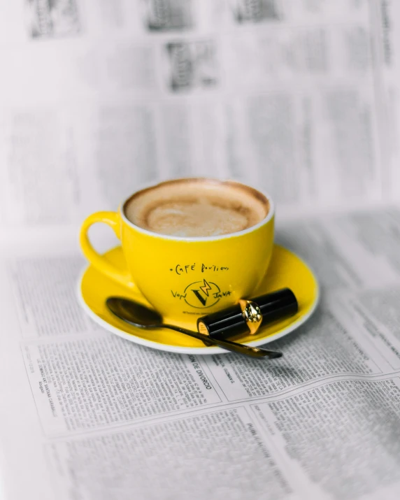 a cappuccino on top of a newspaper with a black fountain pen in the middle