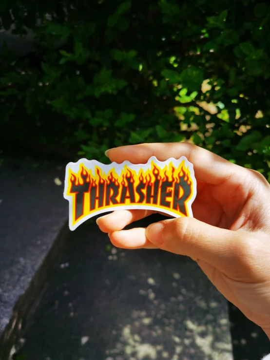 someone is holding a sticker saying thrash on it